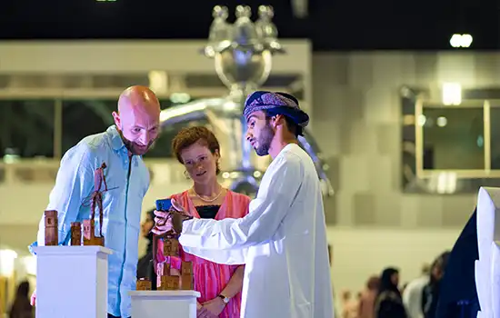 Muscat Art Exhibition 2024 – From October 29 to 31 6 Visitors observing and discussing art pieces at Muscat Art Exhibition 2024.