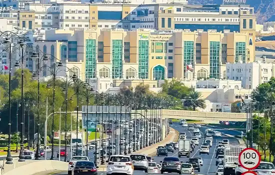 Image of Sultan Qaboos Street with heavy traffic and tall buildings in the background