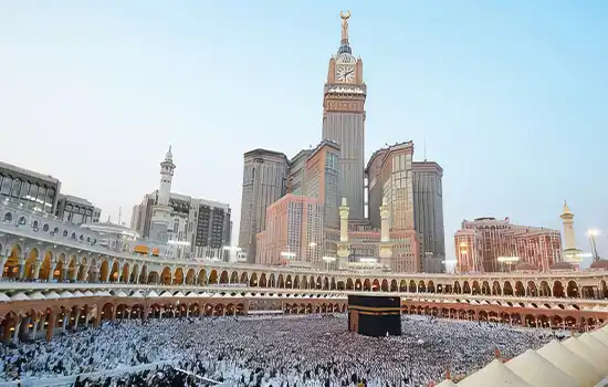 Image of the Kaaba with pilgrims at the Grand Mosque, with the Mecca Clock Tower in the background.