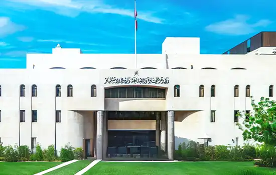 A government building on a sunny day with modern architecture and an entrance sign in Arabic script.