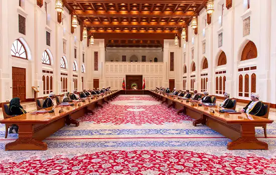 Image of an official session in Oman with representatives in a traditionally designed hall with ornate carpets