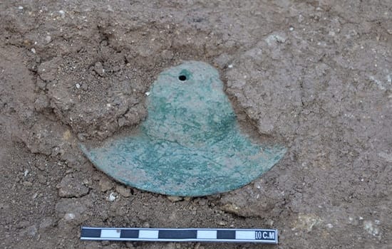 An archaeologist uncovers a historic copper cymbal during excavations at Dahwa-7 site in Saham, Oman