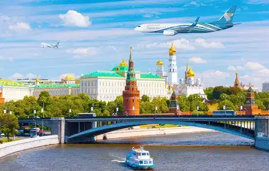 Oman Air aircraft flying over Moscow city with Kremlin and river in the background