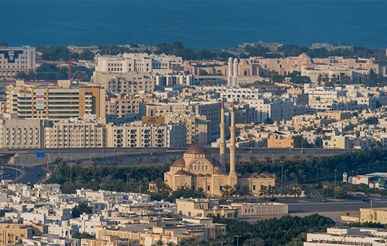 Aerial view of Muscat, Oman, showing residential and commercial buildings amid real estate market growth